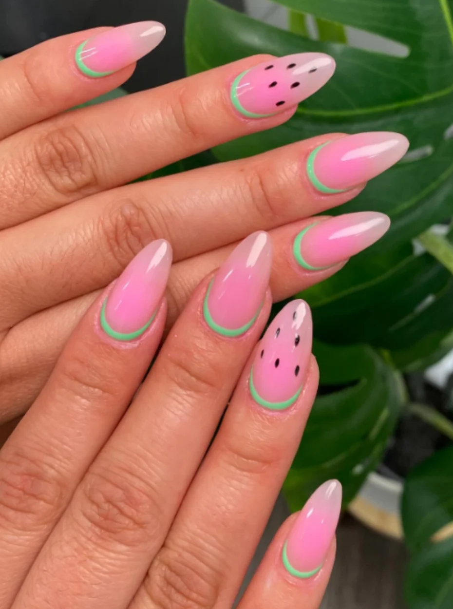 Wassermelonen Nail Art mit rosa Farbverlauf, grünen French Tips und schwarzen Kernen auf mandelförmigen Nägeln – frischer Sommer-Look.