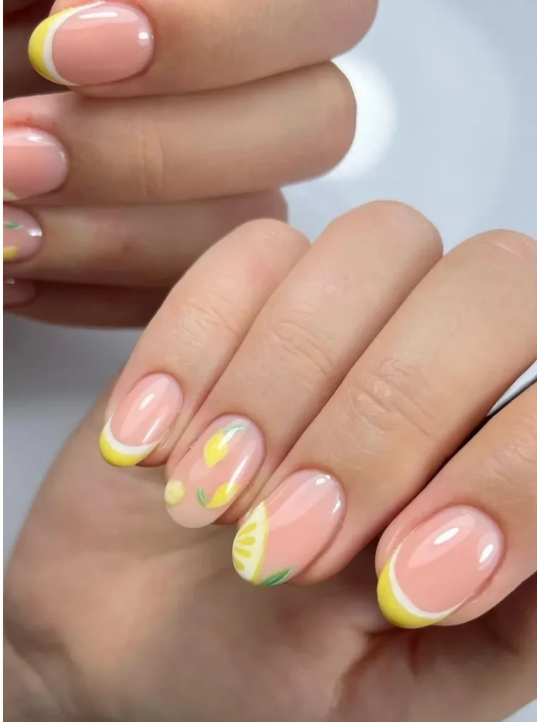 Zitronengelbe French Nails mit handgemalten Zitronenmotiven, gelben Spitzen und glänzender Nude-Basis auf kurzen ovalen Nägeln.